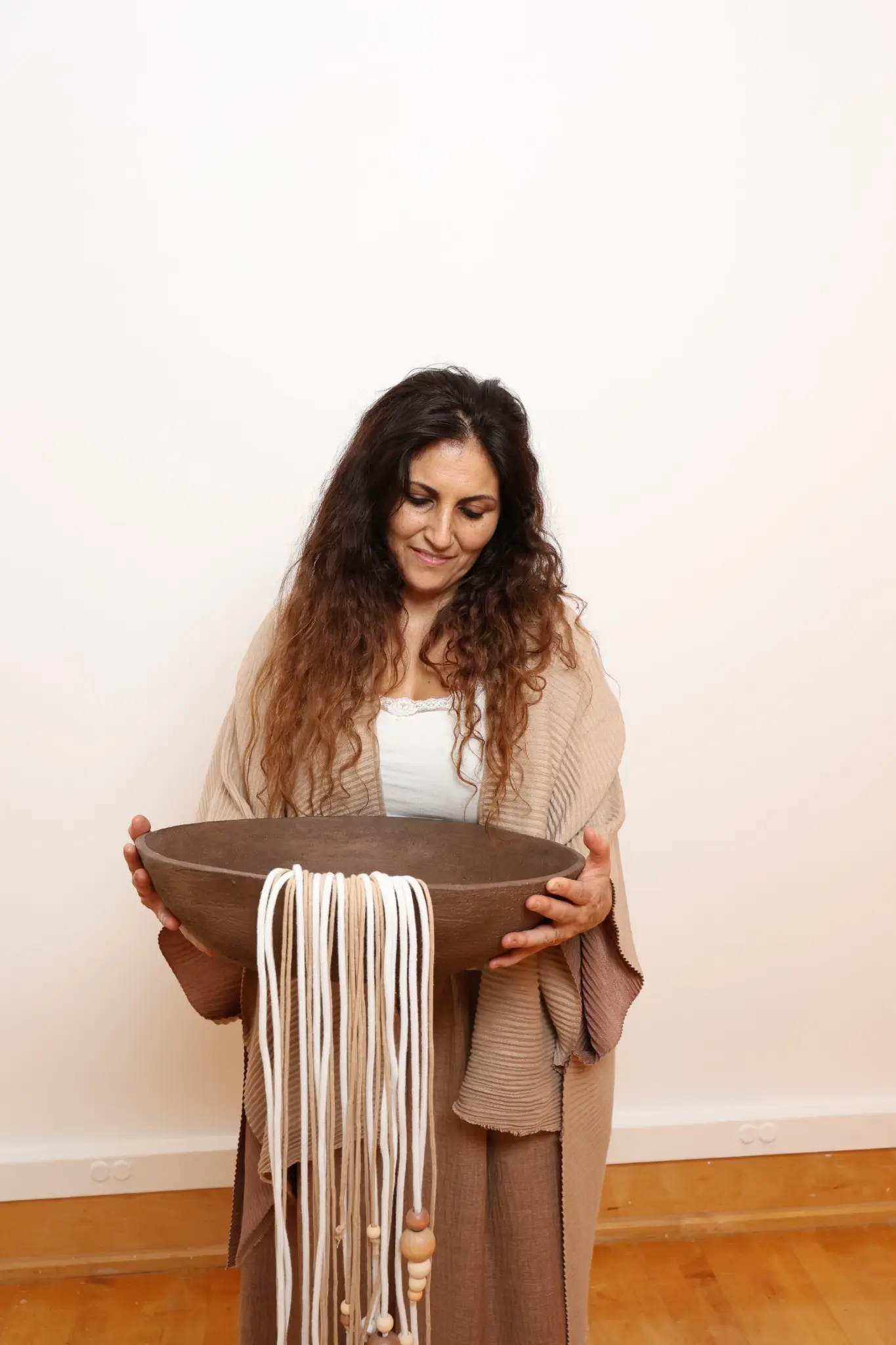 Ceramic artist Maria Emilia Steiner holding a fiber-draped ceramic bowl
