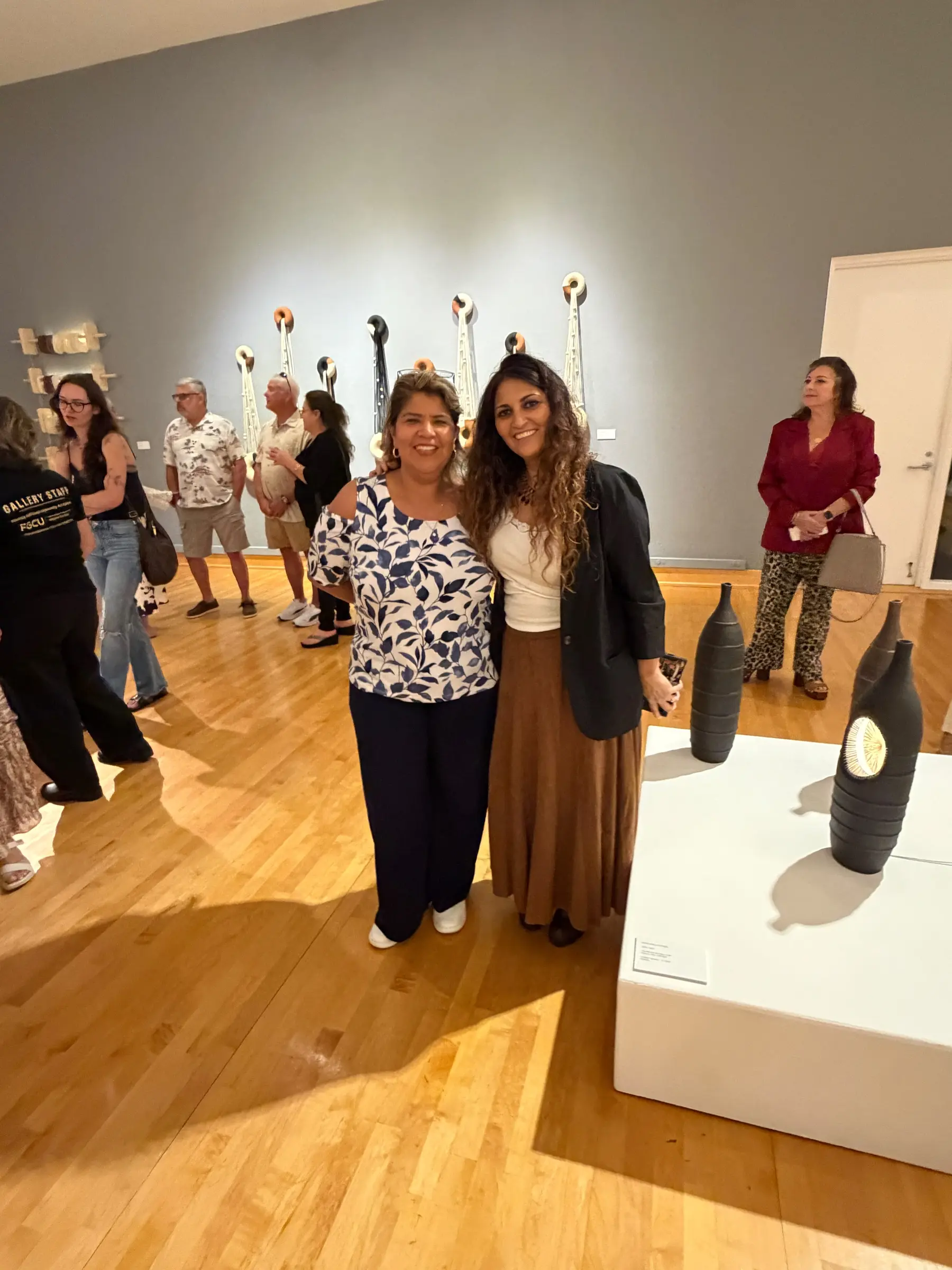 Two guests posing beside the pedestal display at the opening