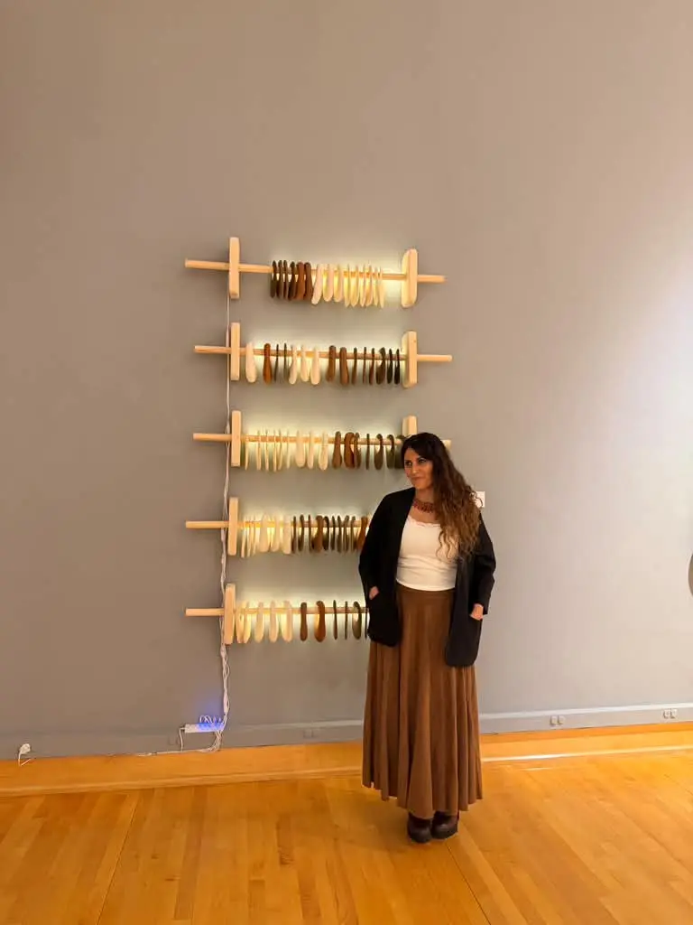 Maria Emilia Steiner standing beside the five-row ceramic wall installation