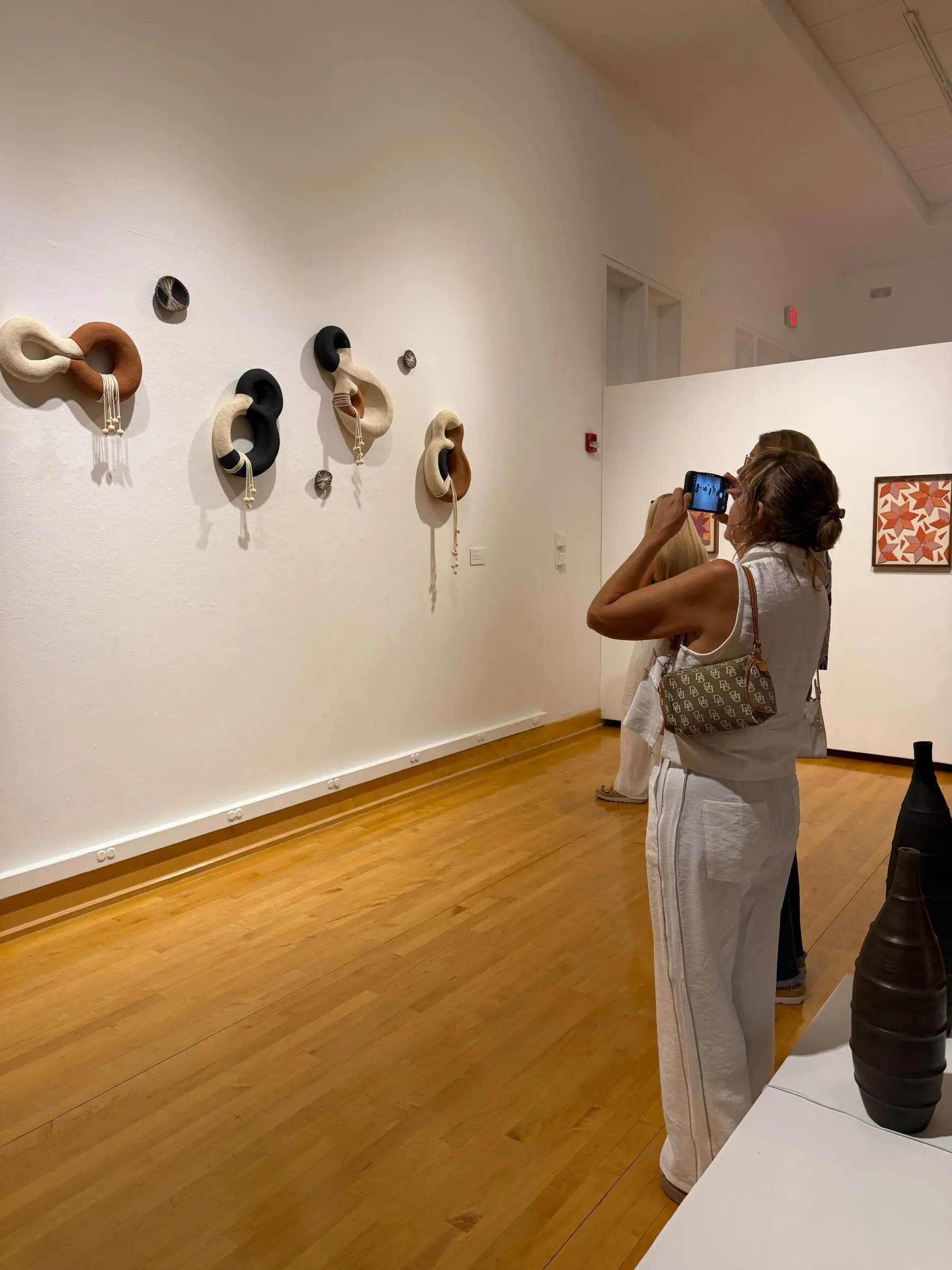 Visitor photographing the ceramic vessels and wall installation