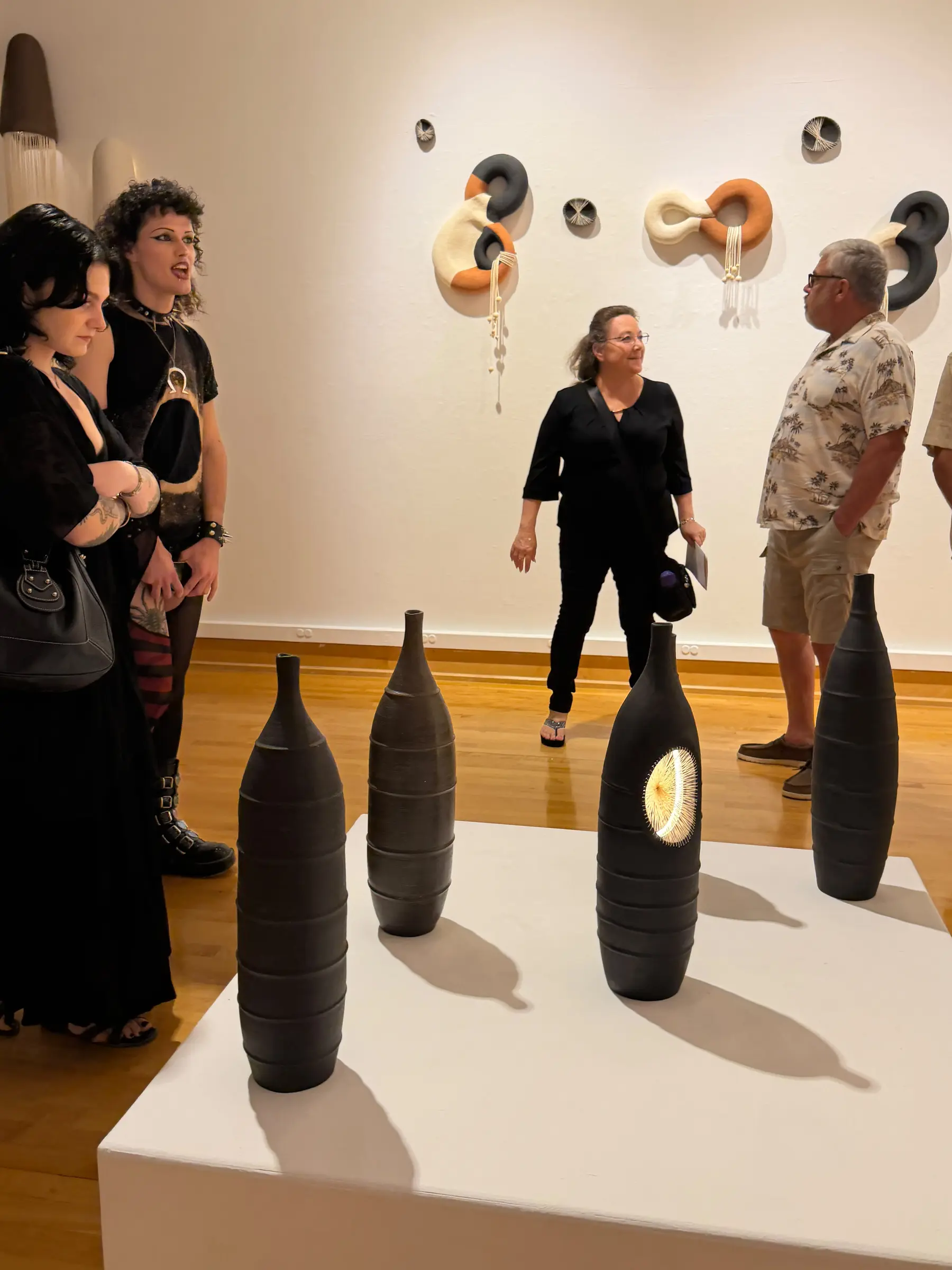 Guests in conversation around the ceramic vessel display