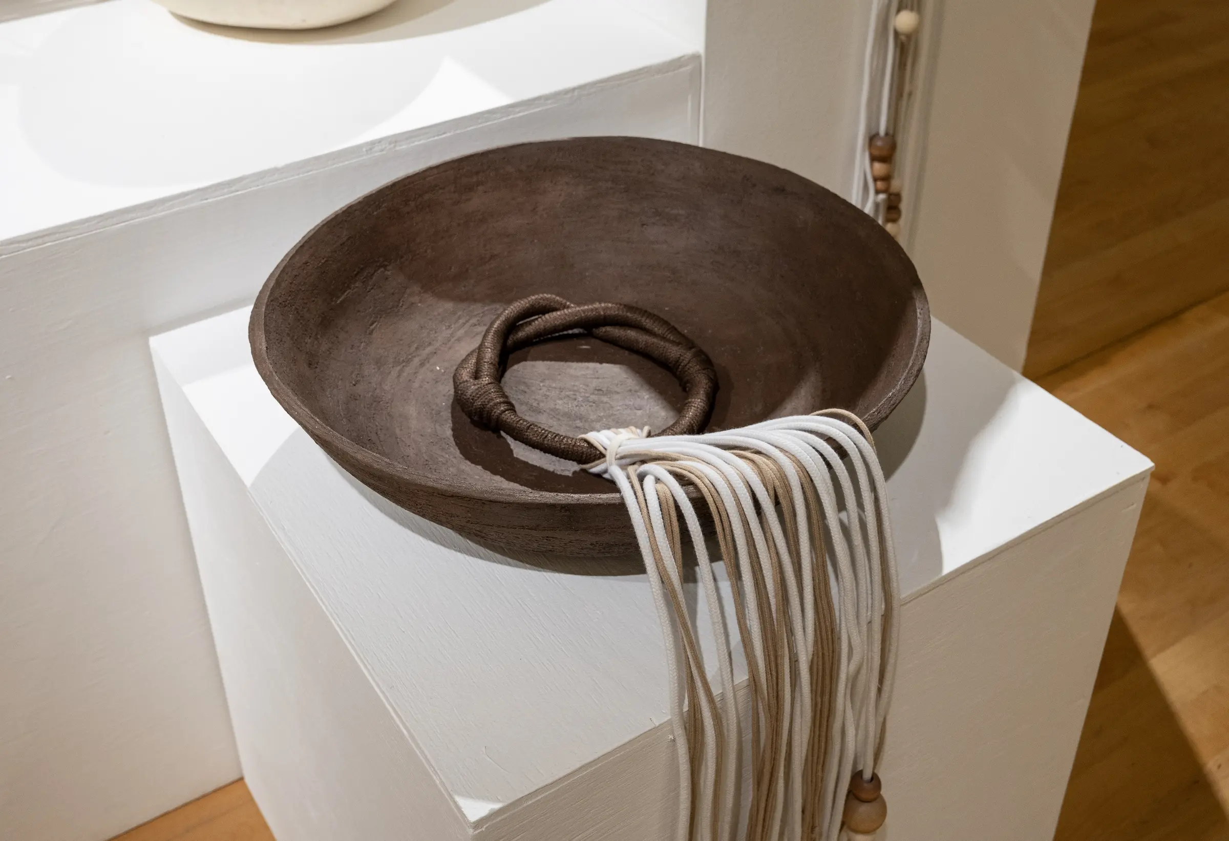 Shallow brown ceramic bowl with white fiber cascading over the pedestal