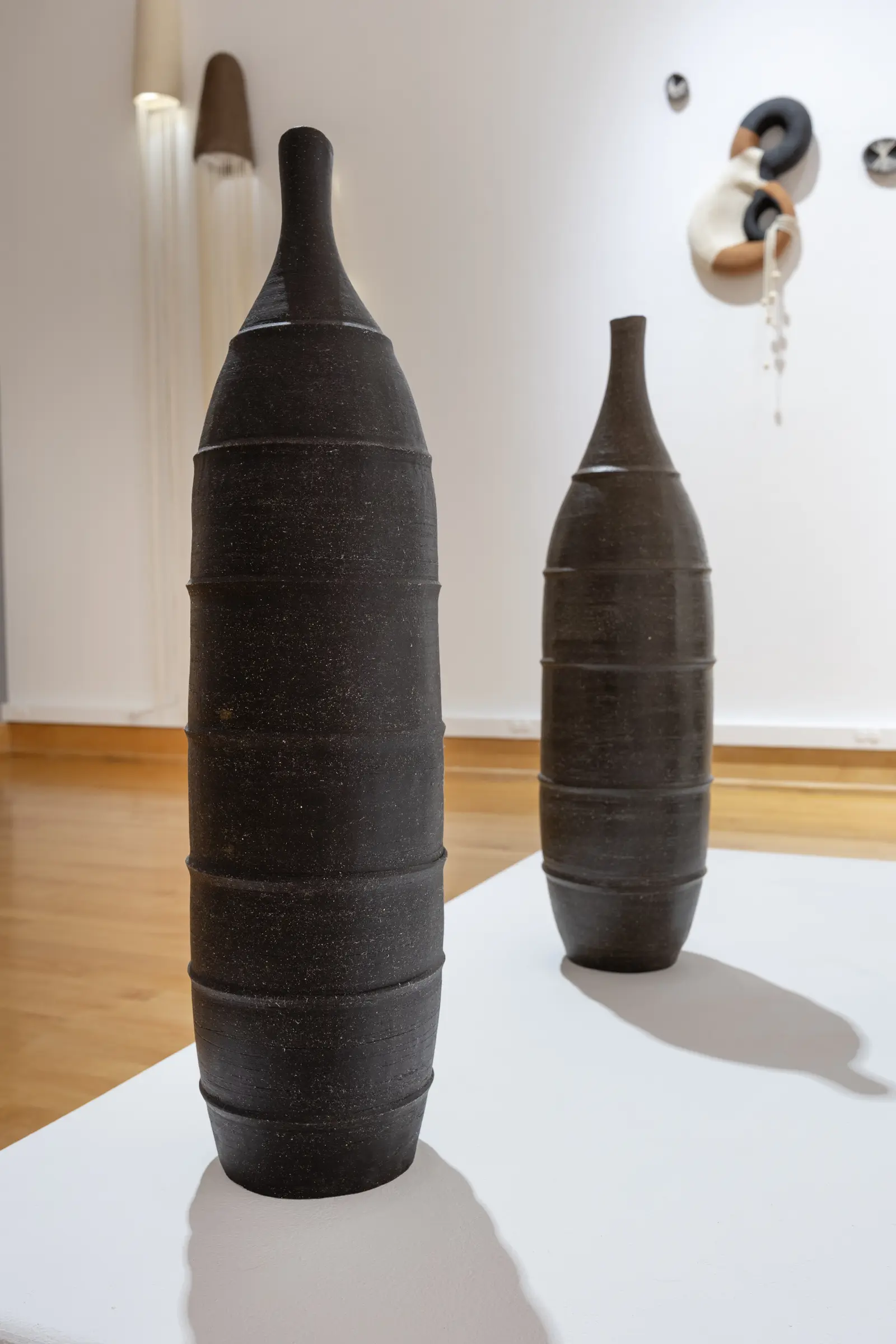 Two tall black ceramic vessels with ridged hand-built surfaces