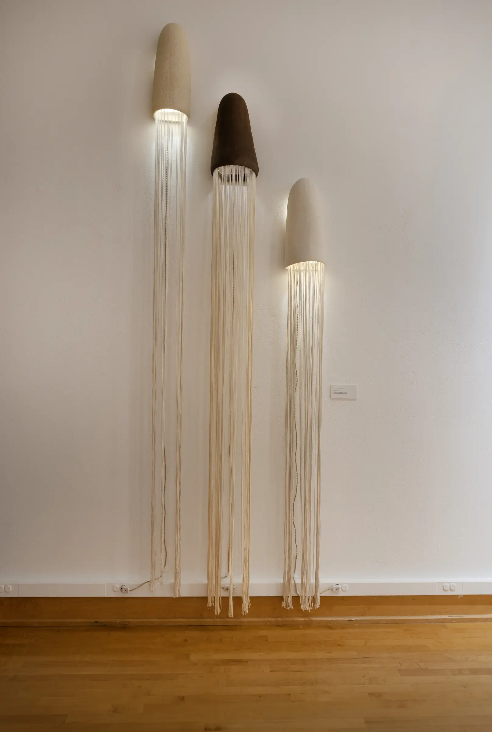 Three tall illuminated ceramic lamps with fiber falling to the floor