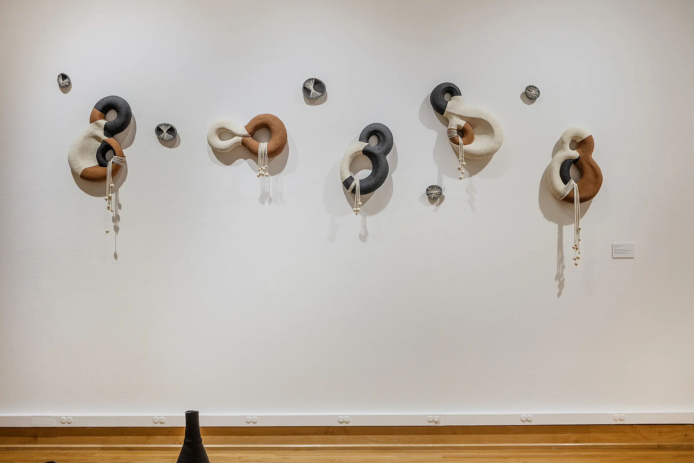 Five interlocking black, brown, and white ceramic wall sculptures