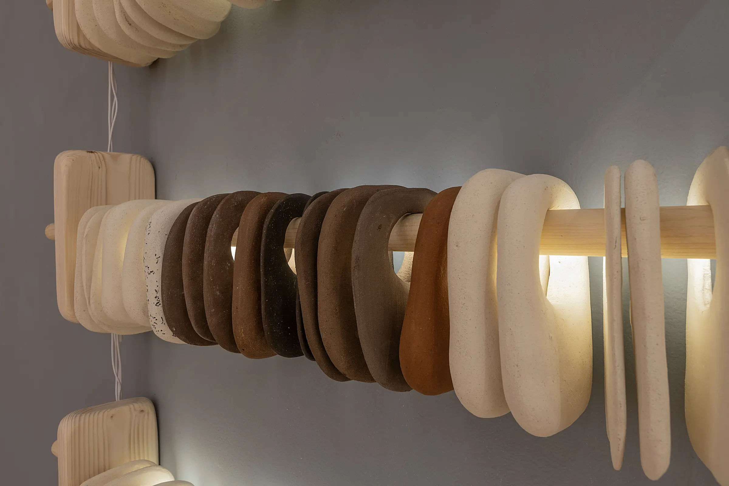 Close detail of brown and white ceramic rings on an illuminated wooden rod