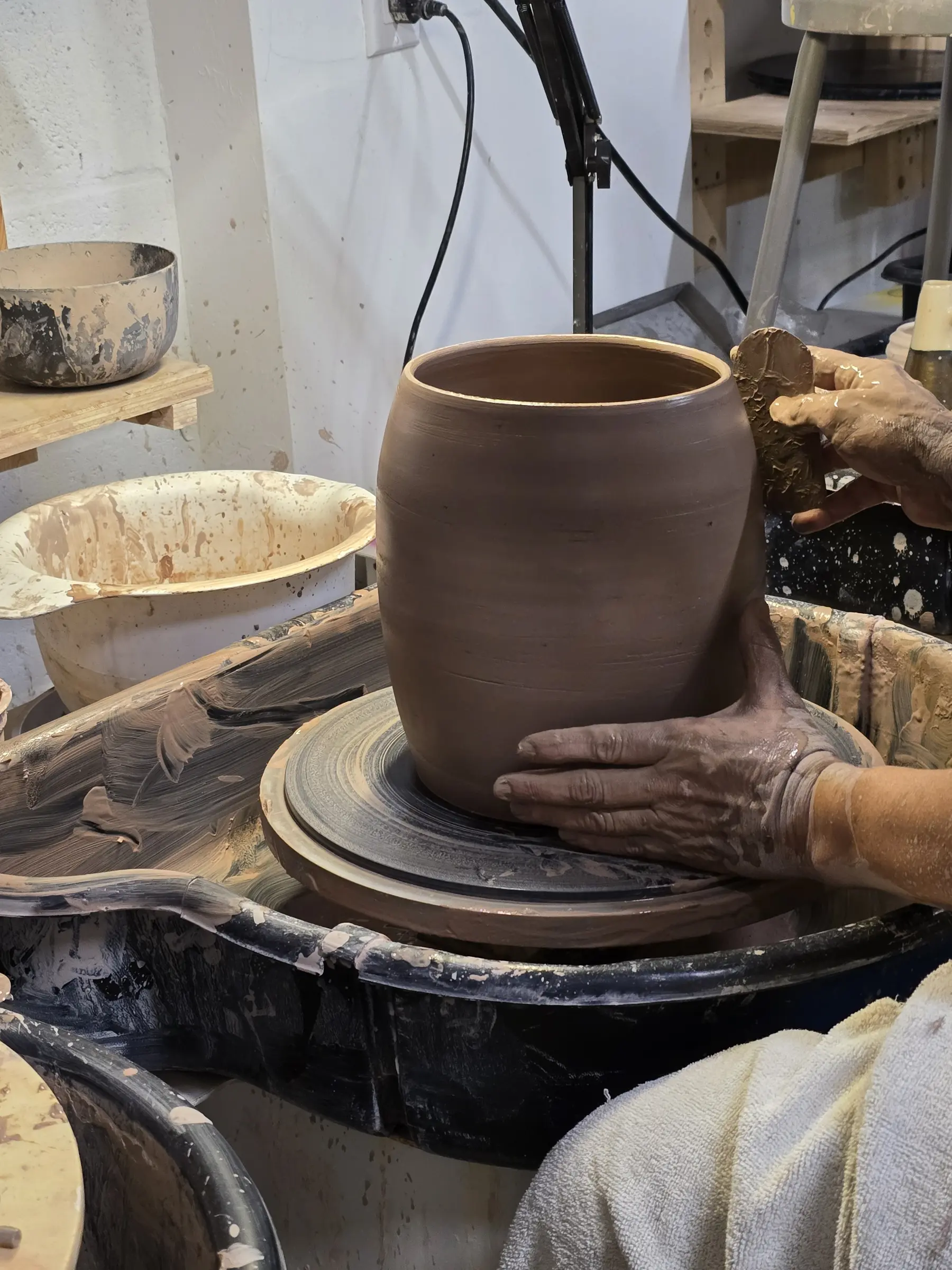 Maria throwing a cylindrical clay vessel on the pottery wheel