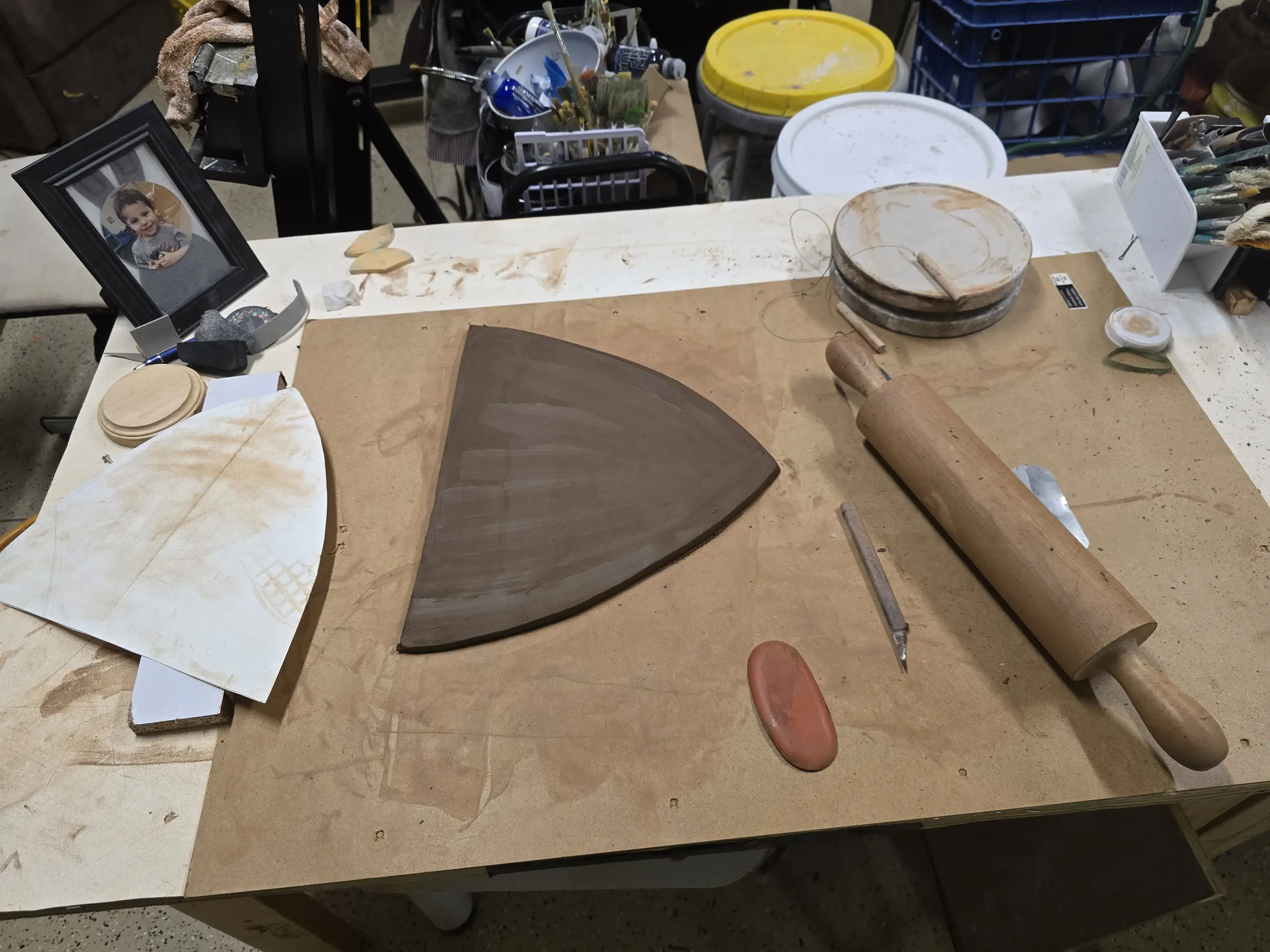 Clay slab, rolling pin, and paper templates arranged on the studio table