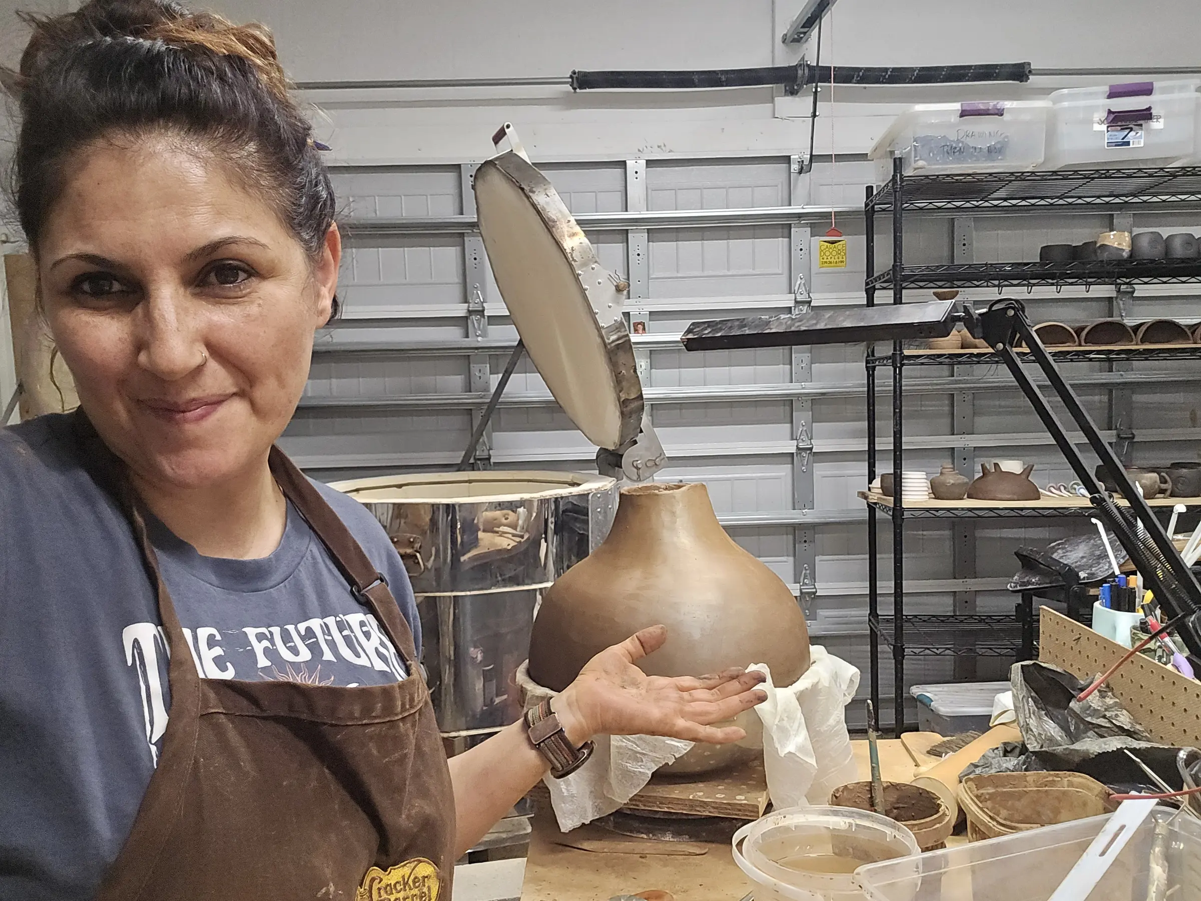 Maria holding a newly formed clay vessel in the studio