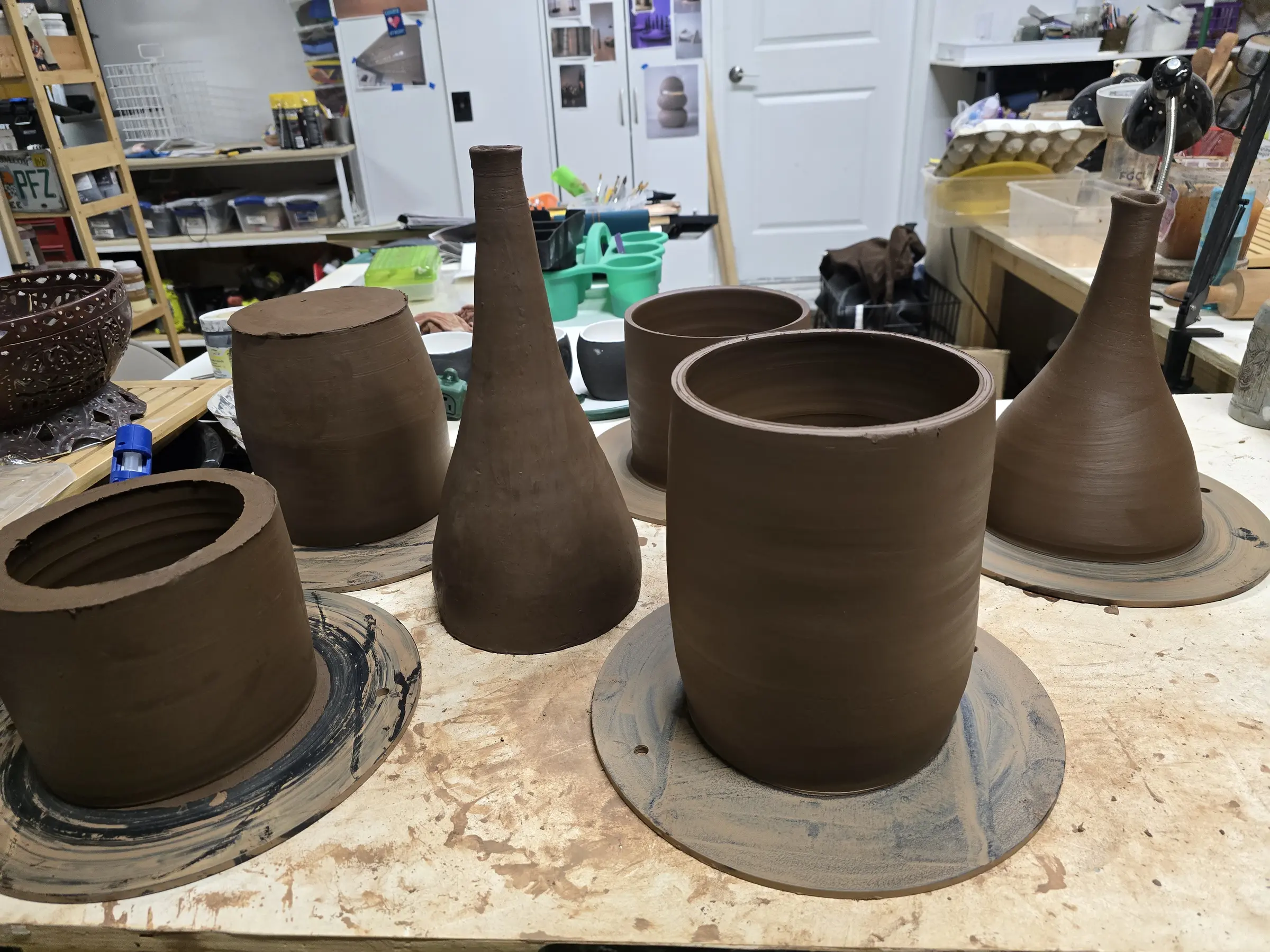 Group of freshly thrown vessels and tapered forms on the worktable