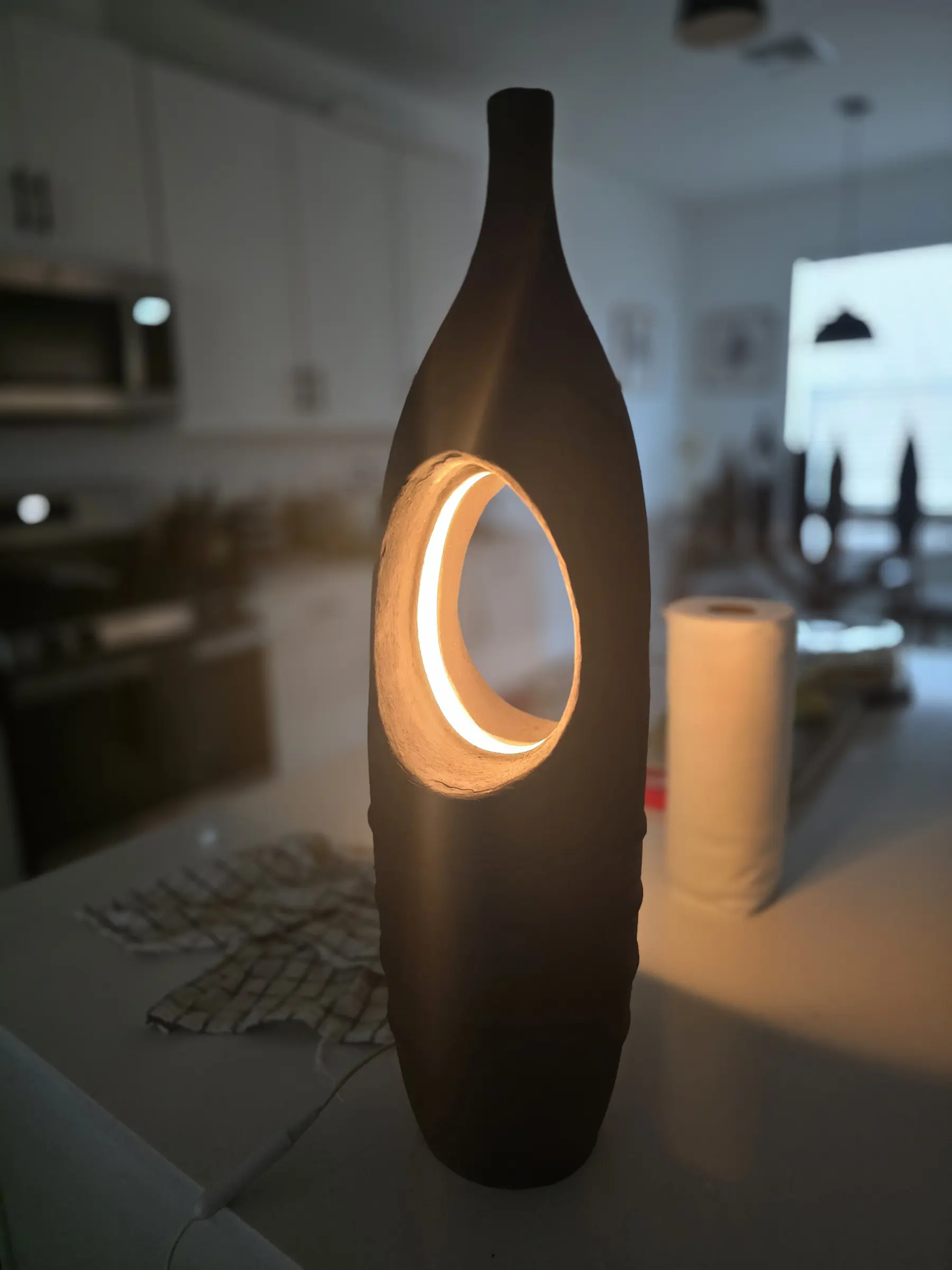 Completed tall ceramic lamp glowing through its circular opening