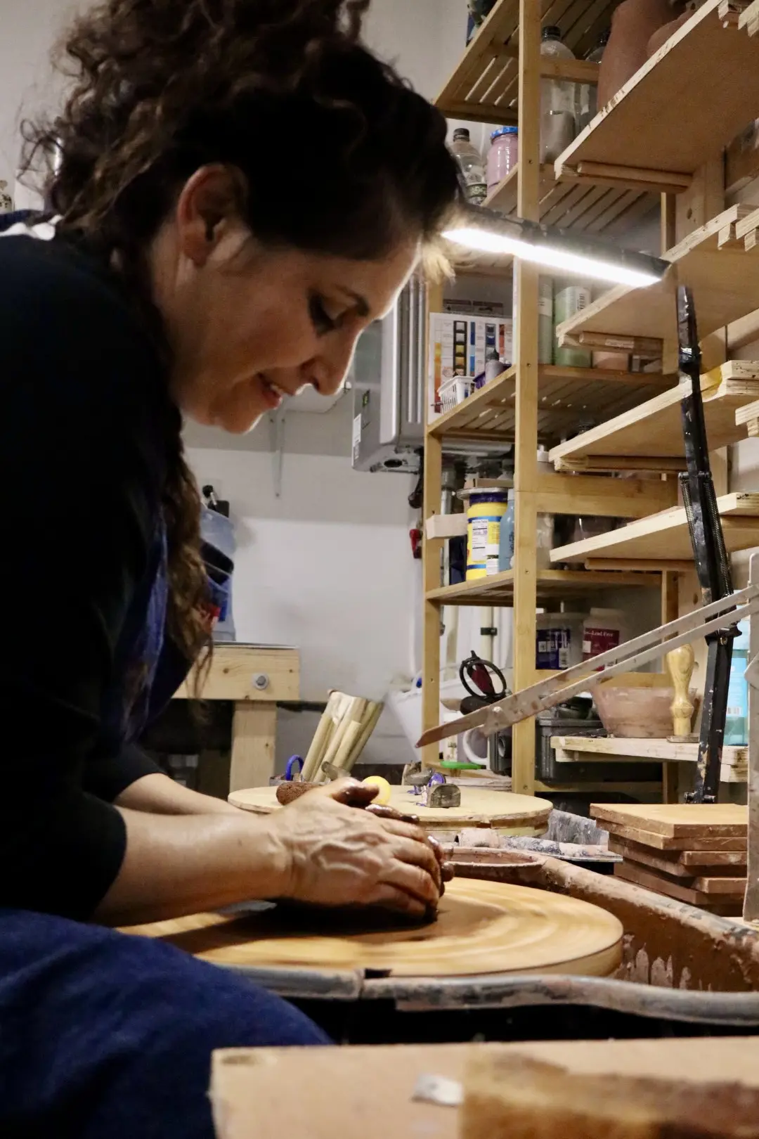 Maria cutting and shaping clay by hand at the studio table