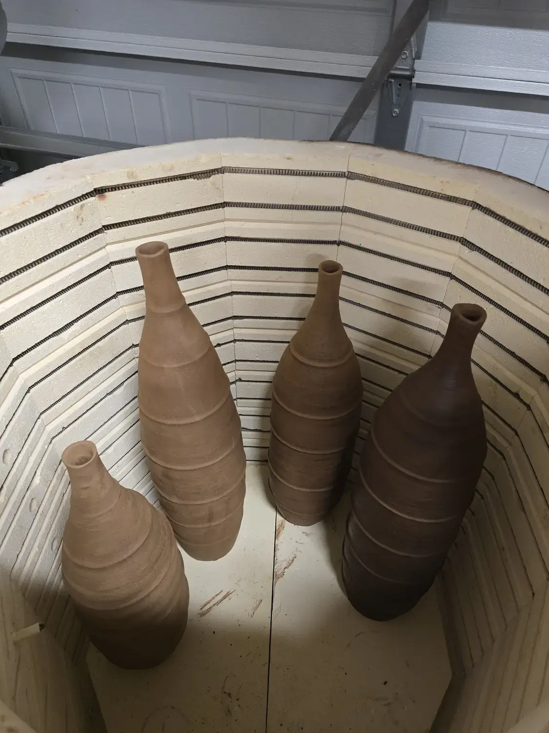 Four narrow ceramic forms arranged inside a kiln