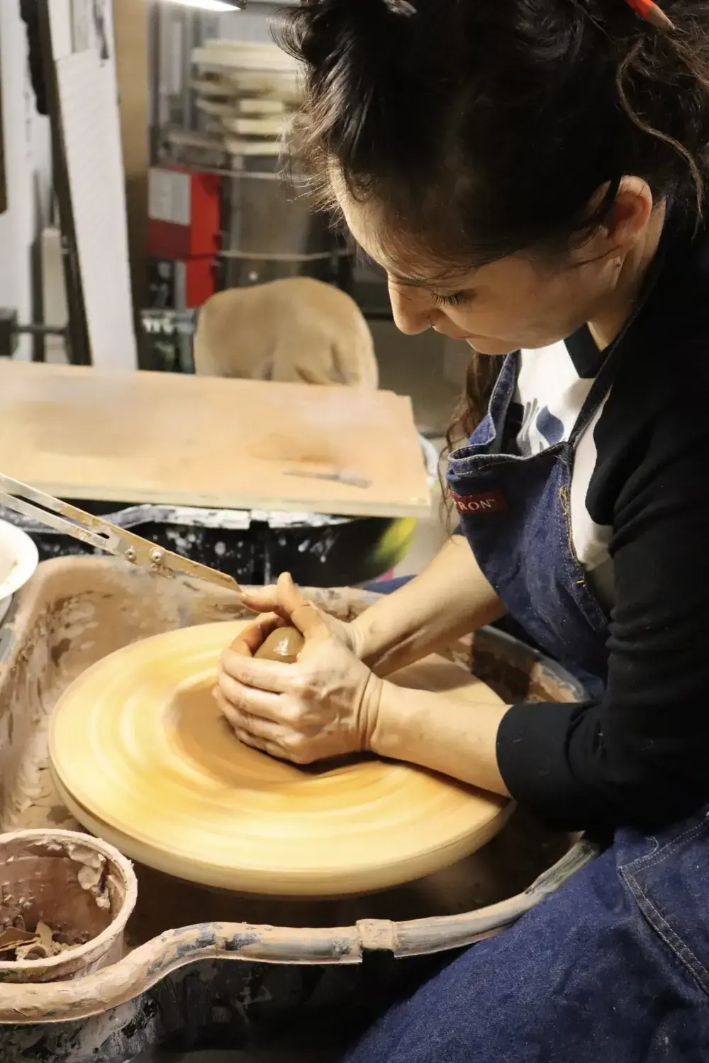 Maria centering clay on a pottery wheel